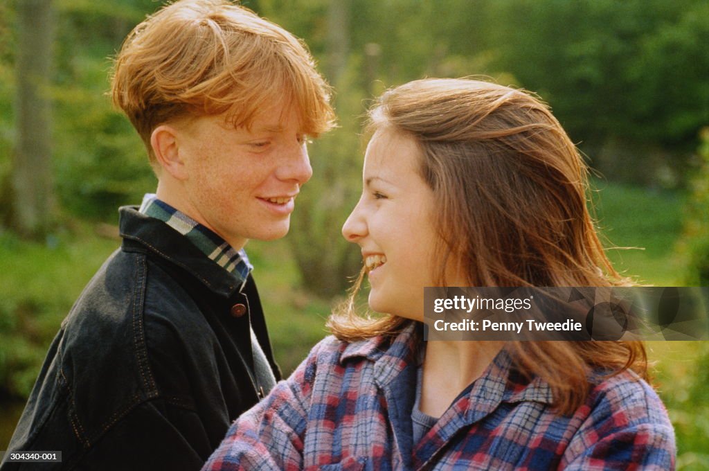 Portrait of teenage couple smiling at each other,outdoors