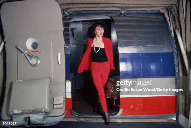 Belgian-born fashion designer Diane von Furstenberg disembarks from a place, dressed in red suit and black tank top, May 1976.