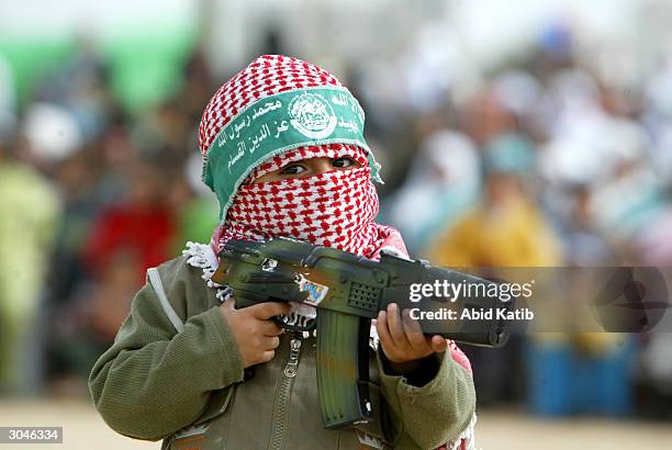 Masked Palestinian boy demonstrates martial arts maneuvers with a plastic gun March 5, 2004 in the Al-Bureij refugee camp in the Gaza Strip. The...