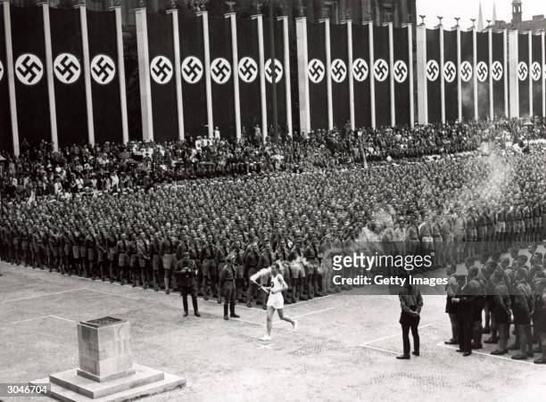 The Olympic torch is carried into the stadium during the opening ceremonies of the XI Olympic Games at the Olympic Stadium in Berlin, Germany, on...