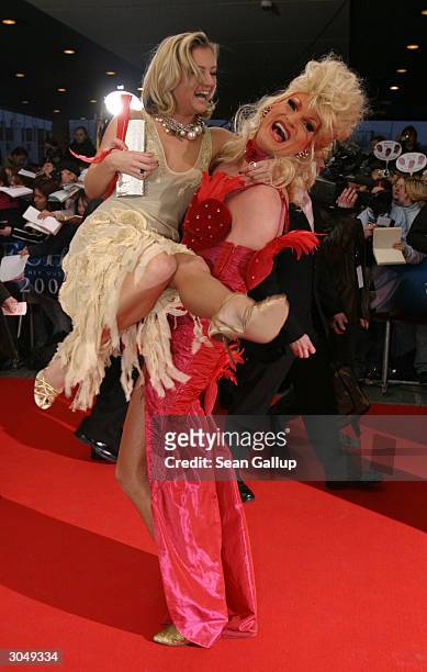 German singer Juliette Schoppmann gets a lift from transvestite Olivia upon their arrival at the ECHO 2004 German music awards on March 6, 2004 in...