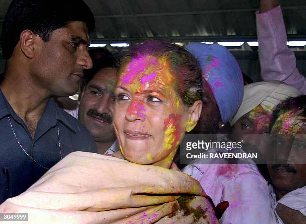 Indian Opposition leader and Congress Party President Sonia Gandhi is greeted by her supporters as she wears a garland and coloured powder on her...