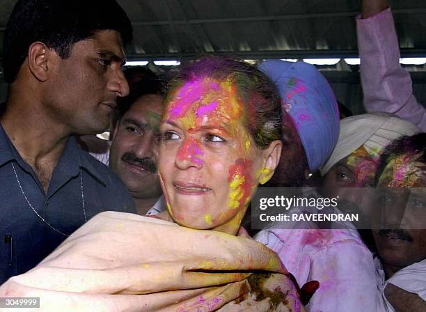 Indian Opposition leader and Congress Party President Sonia Gandhi is greeted by her supporters as she wears a garland and coloured powder on her...