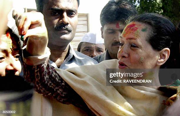 Indian Opposition leader and Congress Party President Sonia Gandhi places a dot of coloured powder on a supporters forehead as she sports coloured...