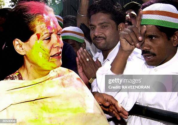 Indian Opposition leader and Congress Party President Sonia Gandhi sports coloured powder marks on her forehead as she is greeted by supporters...