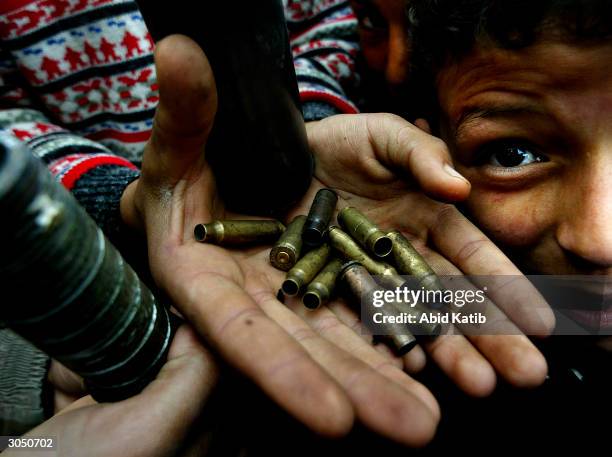 Palestinian boys shows empty bullets during an Israeli incursion to Bureij refugee camp on March 7, 2004 in southern Gaza Strip. Israeli troops...