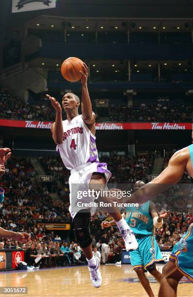 Chris Bosh of the Toronto Raptors attempts a layup in front of Darrell Armstrong of the New Orleans Hornets on March 7, 2004 at the Air Canada Centre...