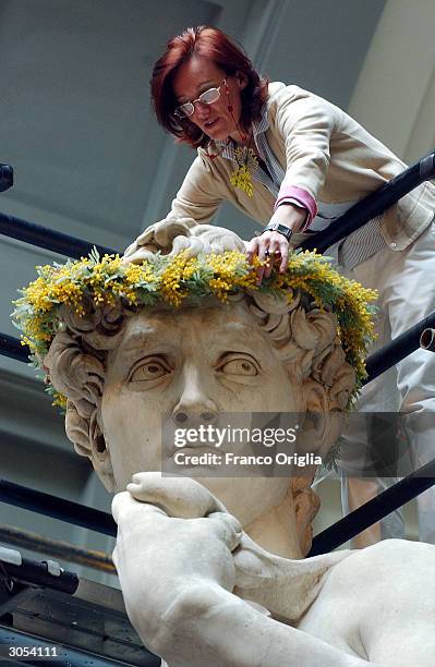 Restorer, Cinzia Parmigoni places a crown of flowers on Michelangelo's David at the Gallery of the Academy, March 8, 2004 in Florence, Italy. In...