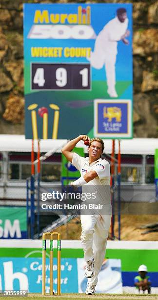 Shane Warne of Australia bowls under a sign counting down his rival spinner, Muttiah Muralitharan of Sri Lanka to 500 wickets, Warne himself...