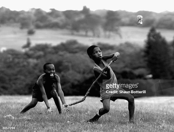 Children playing cricket with a stick and a coke can outside the gates of Buffalo Park on February 15, 2003 in East London, South Africa.