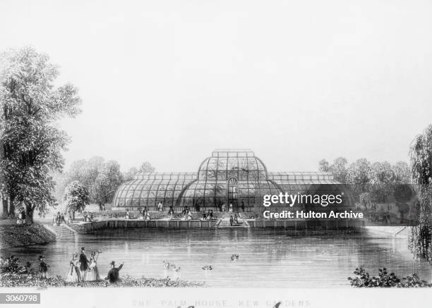 Visitors relax by the ornamental lake in front of the famous Palm House in Kew Gardens, circa 1880.