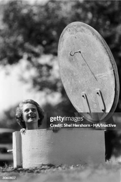 Woman smiles as she looks out from the entrance to an underground bomb fallout shelter, Texas, 1961.