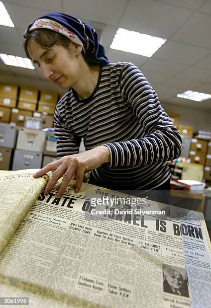 Archivist Elaine Moshe pages through an original edition of The Palestine Post from May 14, 1948 which announces the birth of the State of Israel, in...