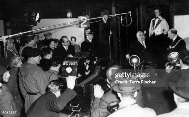 Councillor R Snelgrove, the Mayor of Dover, looking on as the Italian tenor Beniamino Gigli performs for the cameras at Dover Marine Station.