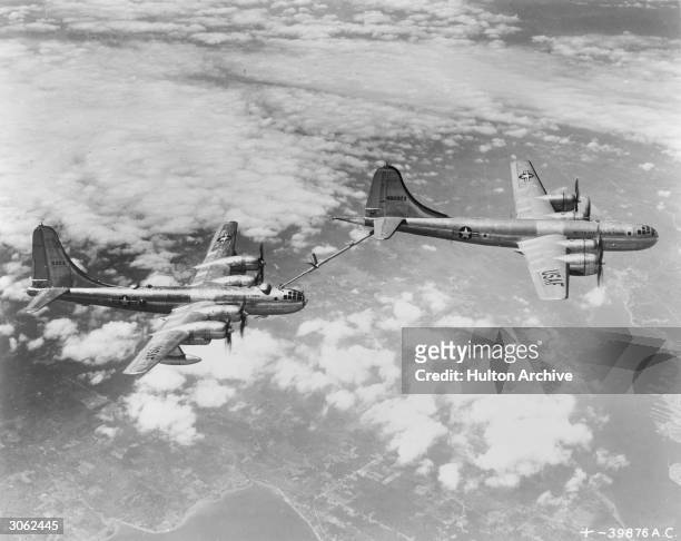 Airforce Boeing B-29 tanker uses a 'flying boom' to refuel a B-50 medium bomber in mid-air.