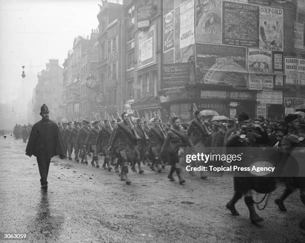 The Canadian Highlanders marching through London during the Lord Mayor's Procession, flanked by a single policeman.