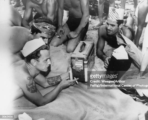 An American sailor listens to the baseball game on the radio, whilst subathing on New York's Coney Island beach.