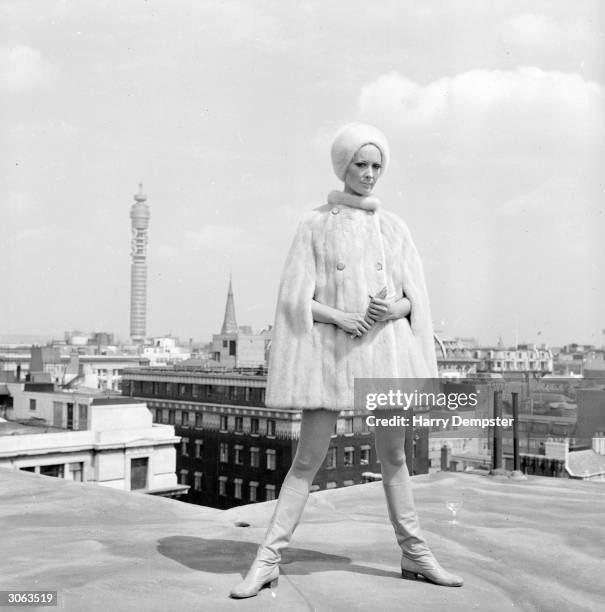 Ruth Dumer models a white mink cape and hat costing ?756 on a rooftop near the Post Office Tower.