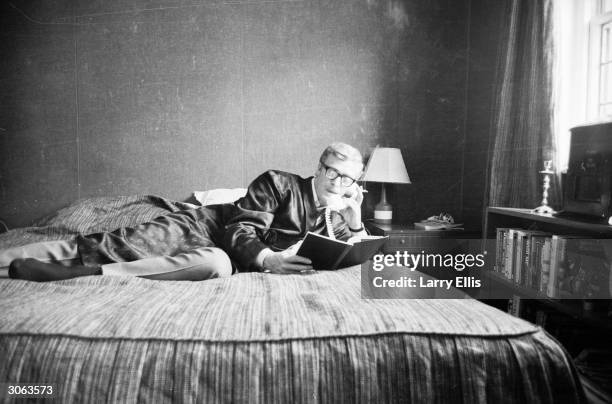 British actor Michael Caine makes himself comfortable with a book and a telephone.