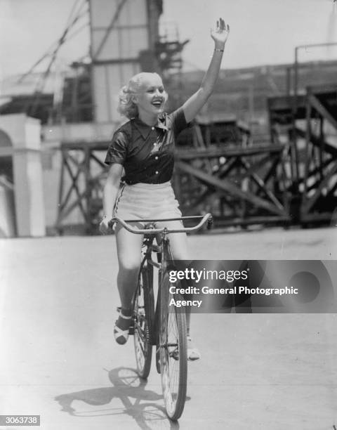 American actress Betty Grable riding a bicycle.