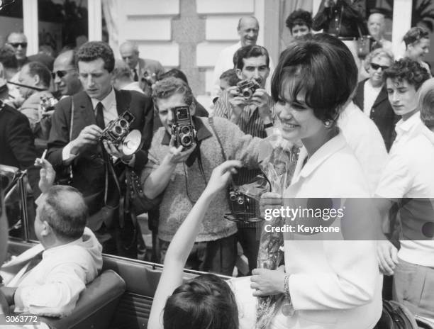 Italian actress Claudia Cardinale arrives at Cannes, amidst a crowd of fans and photographers.