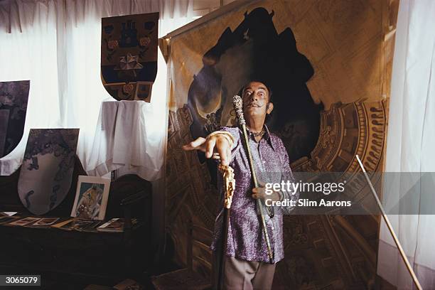 With some of his works at Port Ligat, Costa Brava, painter Salvador Dali in a characteristic pose with his trademark walking-stick.