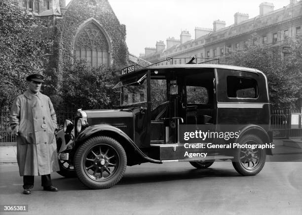 Cab driver stands by his taxi in a London street.