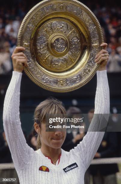 Chris Evert of the USA holds up the women's singles trophy at Wimbledon, London.