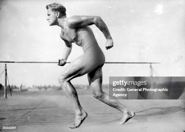 In the Berlin stadium a sprinting and nude German athlete clasps a javelin as he runs.