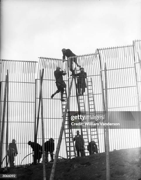 Workers constructing a 17-foot-high fence around the new dell for the tigers at Whipsnade Zoological Park, Bedfordshire, in preparation for the...