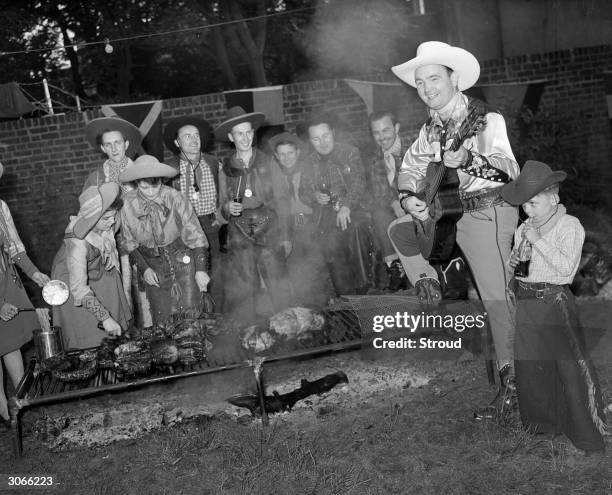 Cowboy Jimmy Hawthorn entertains at a 'western' barbecue with a song on his guitar.