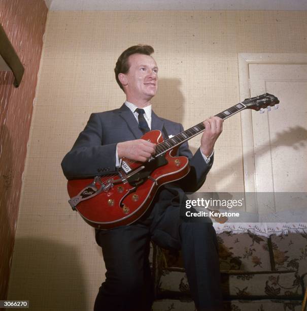 English guitarist Bert Weedon, popular in Britain during the 50's, at his home in Wembley, playing the guitar.
