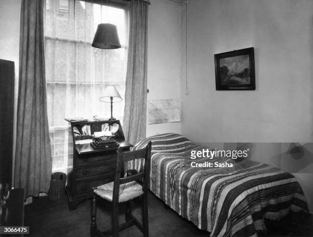 Bedroom in author-actor Emlyn Williams' house. Beside a divan bed is a desk bureau with a typewriter and a lamp.