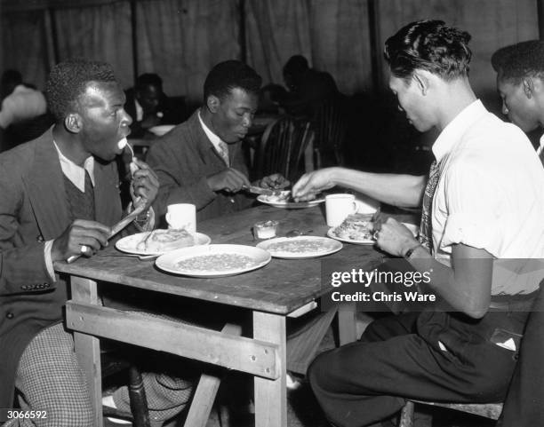 Jamaican men, who arrived in Britain on HMT Empire Windrush on 22nd June, having a meal in a canteen marquee on Clapham Common to get a meal, London,...