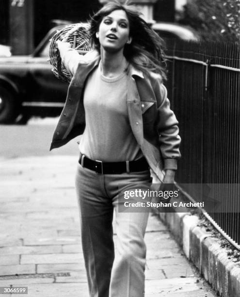 Model and actress Jane Birkin swings a basket along a London street.