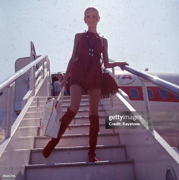 British fashion model Twiggy, born Leslie Hornby disembarks from an aircraft at London Airport.