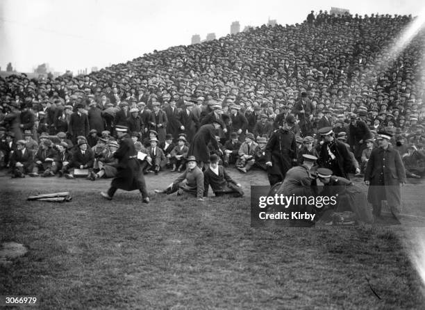 Spectators at a Southampton v Sheffield United football match at Chelsea, overflow onto the pitch where one is being attended to by St John's...