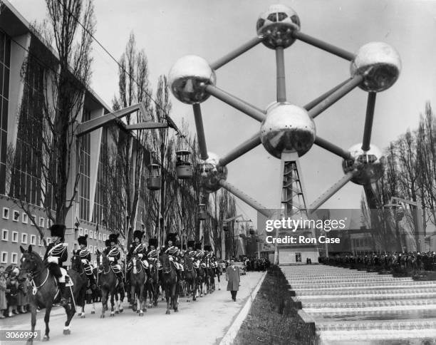 Mounted soldiers make a royal escort for King Baudouin of the Belgians at the opening of the Brussels Exhibition. The Atomium is in the background.