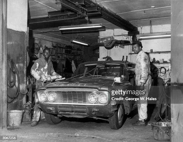 On the left Milton Parks from St Thomas and Dennis Ebanks from Kingston Jamaica at work in a motot repair shop after coming to England to help in the...