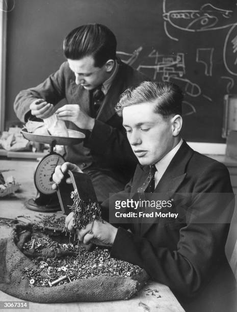 Prefect G Jennings and S C Ellis of Acton County School use a magnet and scales to sort the sweepings from an aircraft factory. They have already...