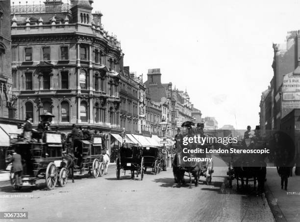 Horse drawn carriages on a busy Oxford Street in London.