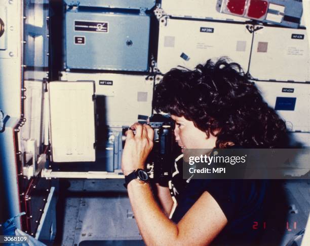 Astronaut Sally Kirsten Ride, the first American woman in space takes a photograph during her earth orbit in the Challenger shuttle STS-7.