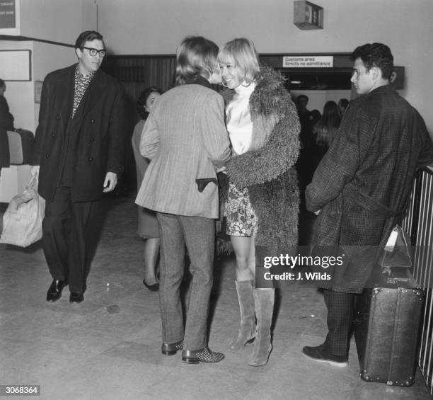 Brian Jones of the Rolling Stones greets actress Anita Pallenberg as she arrives at London Airport