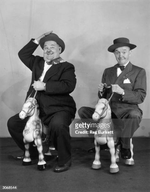 Comedian and actor Oliver Hardy and his partner Stan Laurel on a pair of wooden horses.