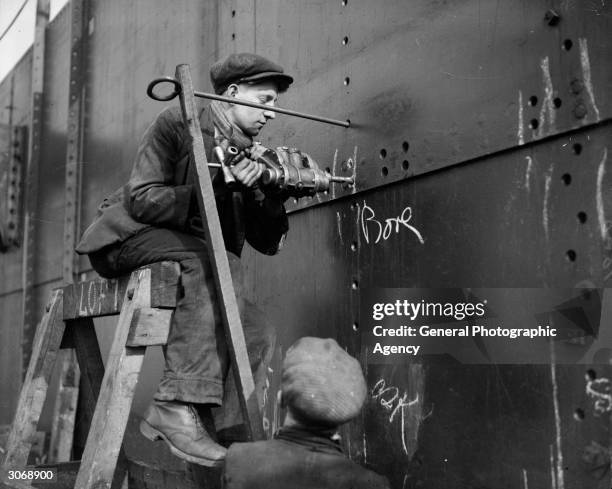 Riveter working on the hull of the liner Queen Mary during her construction at Clydebank.