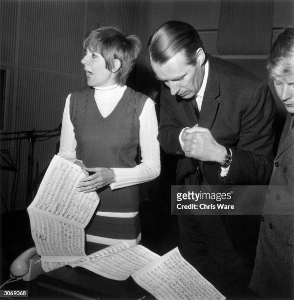 English pop singer Cilla Black in the studio with George Martin, recording the title song to her first film 'Work is a Four Letter Word'.