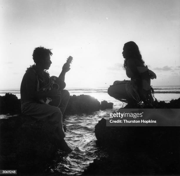 Young man serenades his sweetheart with a guitar on a rocky promontory of Tonga, an island in the Pacific Ocean. Original Publication: Picture Post -...