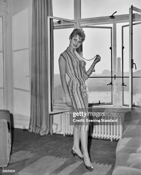 French actress Brigitte Bardot standing at the window of her room at the Savoy Hotel, London, October 27th 1956. She is in London to attend the 1956...