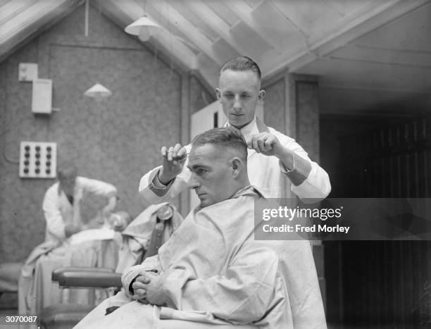 New Zealand batsman, 'Stewie' Dempster' checking a client's haircut in a barber's shop which he has opened in Blackpool.