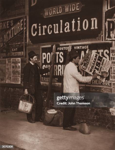 Victorian bill stickers paste placards advertising Madame Tussaud's waxworks museum in London. Original Publication: From 'Street Life In London' by...